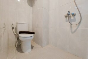 Un baño con inodoro, ducha y paredes de azulejos.