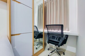 Une pièce avec une armoire à portes miroir, un fauteuil de bureau noir et une fenêtre avec des rideaux.