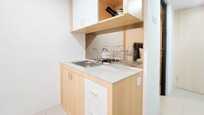 Cocina compacta con lavabo, armarios de madera y escurreplatos.