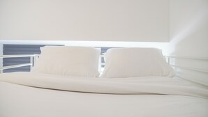 A bed with white bedding and two pillows. - Simply Look And Homey Studio Tokyo Riverside Pik 2 Apartment (Teluknaga)