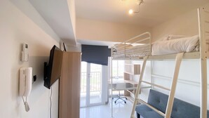 A bunk bed room with a desk, chair, and a phone on the wall. - Simply Look And Homey Studio Tokyo Riverside Pik 2 Apartment (Teluknaga)
