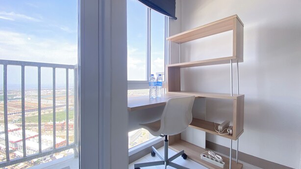 A modern office space with a desk, chair, and shelves, overlooking a cityscape. - Simply Look And Homey Studio Tokyo Riverside Pik 2 Apartment (Teluknaga)