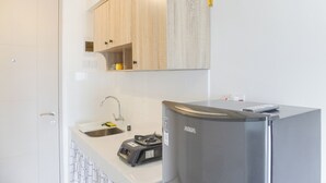 A modern kitchen with white cabinets, a stainless steel refrigerator, and a compact sink area. - Simply Look And Homey Studio Tokyo Riverside Pik 2 Apartment (Teluknaga)