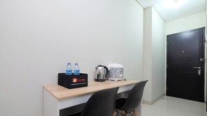 A small kitchenette with a countertop, two black chairs, a coffee maker, a kettle, and a box of travel essentials. - Comfort Studio For 4 Pax At Nifarro Park Apartment (Jakarta)