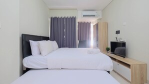 A modern hotel room with a large bed, a flat-screen TV, a wooden console table, and an air conditioning unit. - Comfort Studio For 4 Pax At Nifarro Park Apartment (Jakarta)