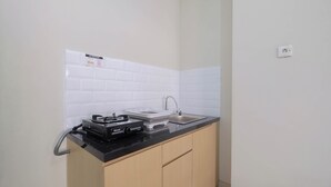 A small kitchen with a black countertop, a sink, and a stove. - Comfort Studio For 4 Pax At Nifarro Park Apartment (Jakarta)