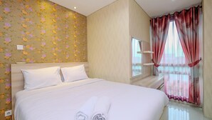 A hotel room with a bed, a window with curtains, a wall with floral wallpaper, and a small table with a lamp. - Nice And Comfort 2Br Apartment At Woodland Park Residence (Jakarta)