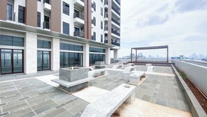 A rooftop terrace with stone seating and a pergola, overlooking a city skyline. - Brand New And Comfort Studio At Vasaka Solterra Apartment (Jakarta)