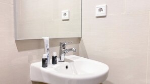A white sink with a chrome faucet, two toiletries, and a mirror above it. - Brand New And Comfort Studio At Vasaka Solterra Apartment (Jakarta)