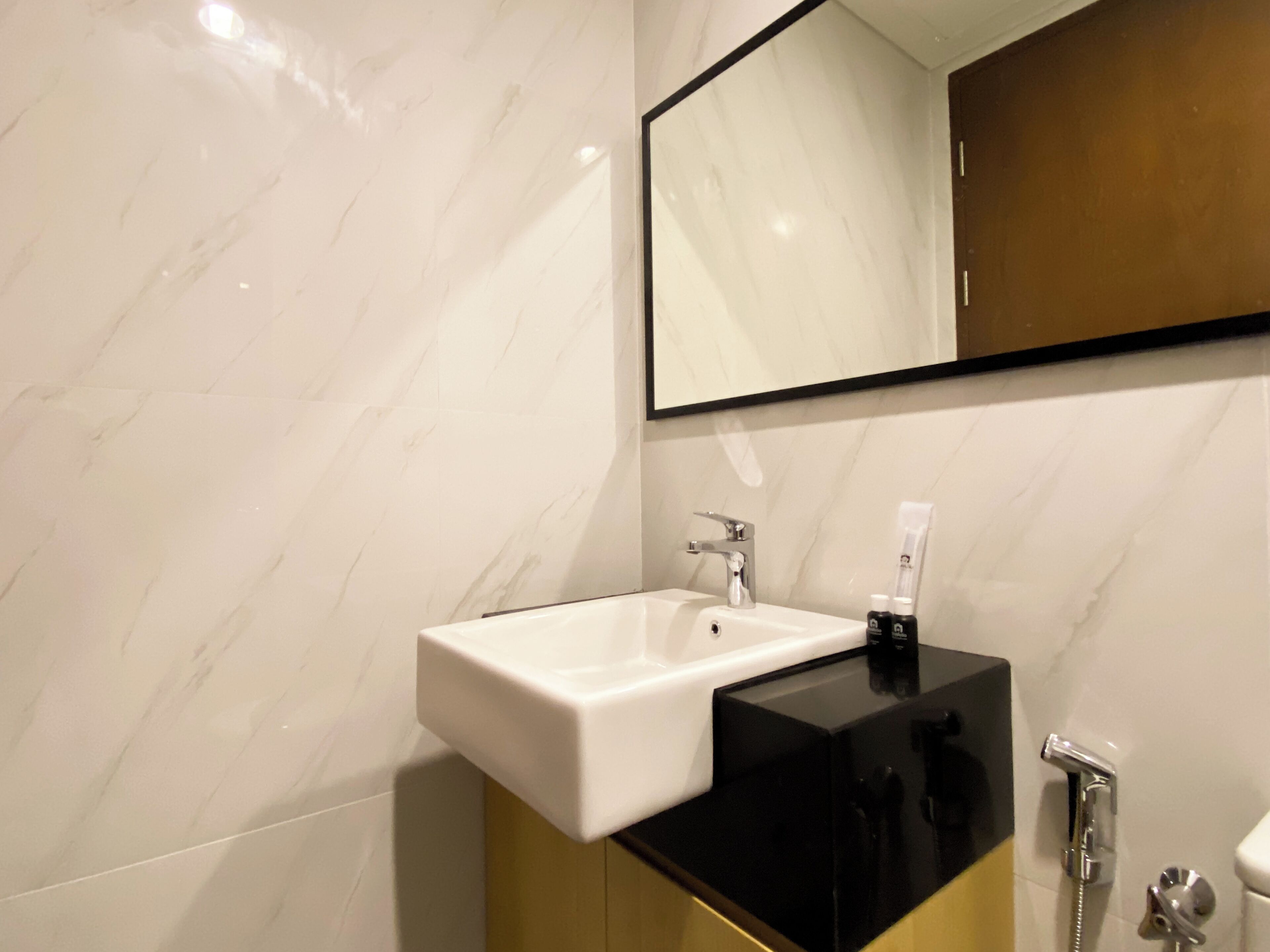 A bathroom with a white sink, black countertop, and a mirror above it.