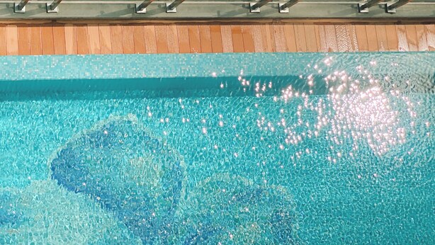 Klar udsigt til en swimmingpool med en træterrasse ovenover.