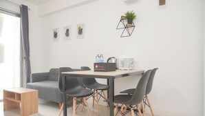 A modern, well-lit room with a dining table, chairs, a sofa, and a coffee machine. - Best Deal And Comfort 3Br At Bassura City Apartment (Jakarta)