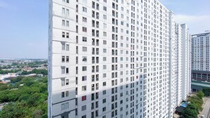 A high-rise building with a uniform facade, multiple balconies, and a clear view of the surrounding urban landscape. - Best Deal And Comfort 3Br At Bassura City Apartment (Jakarta)