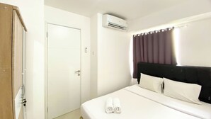 Quarto de hotel com cama, porta, ar condicionado e cortina.