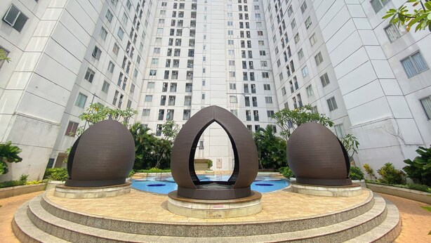 Um edifício moderno com uma escultura central e uma piscina em primeiro plano.