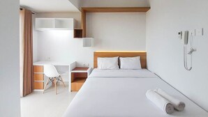A modern hotel room with a bed, a desk, and a chair.