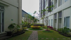 A courtyard with a gravel path, surrounded by greenery and potted plants.