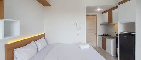 Una habitación de hotel moderna con una cama grande, una pequeña kitchenette y una viga de madera en el techo.