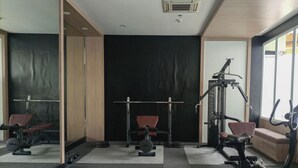 A gym with exercise equipment, a bench, and a mirror.