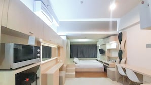 Ein modernes Hotelzimmer mit Bett, Schreibtisch, Stuhl, Mikrowelle und Fernseher.