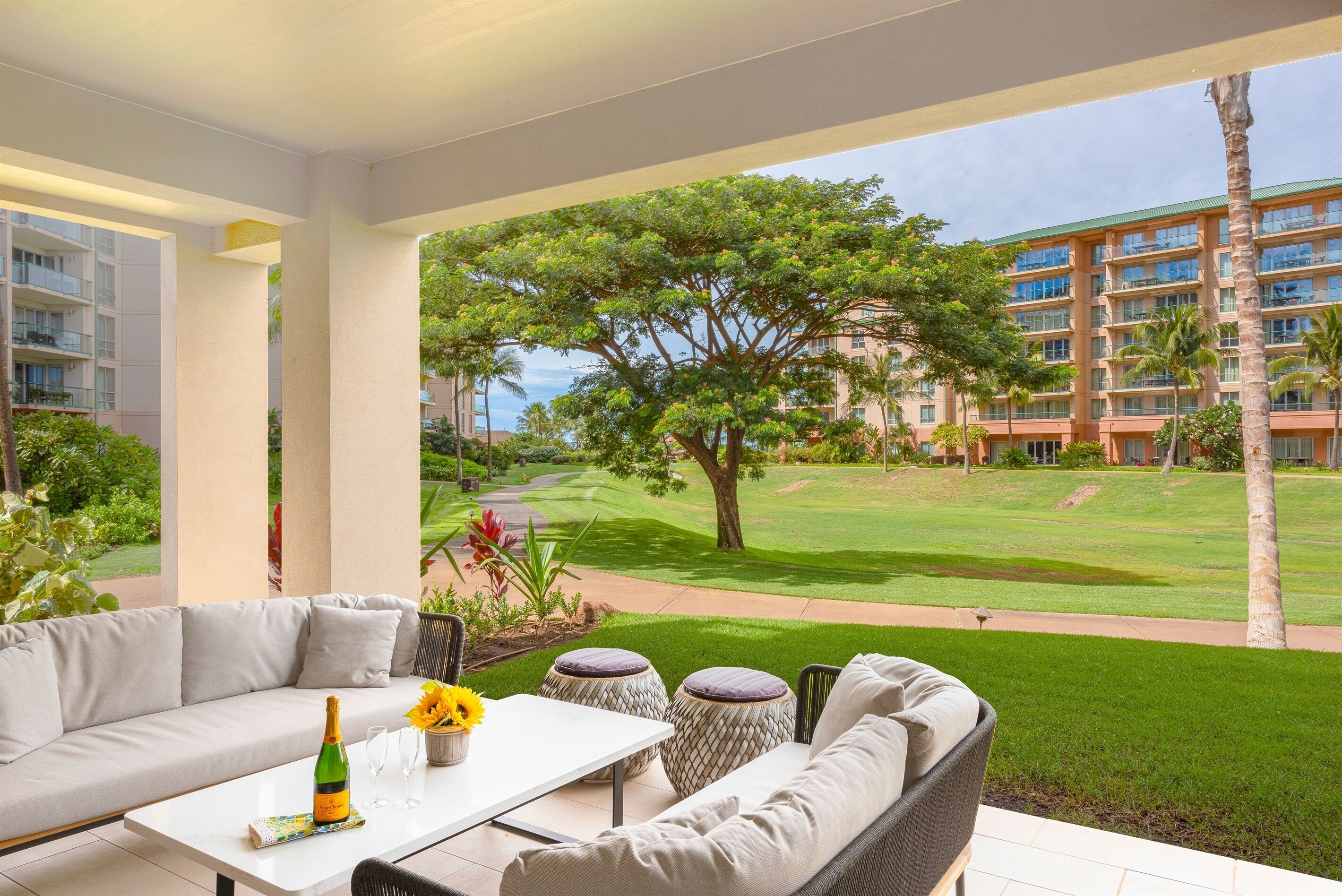 A modern outdoor seating area with a sofa, table, and decorative items, overlooking a well-maintained lawn and a golf course.