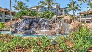 A resort with a waterfall, palm trees, and a pool. - Welcome to Luana Garden Villa ground level Oceanfront Honua Kai Resort (Lahaina)