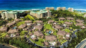 A resort with multiple bungalow-style buildings, a central pool, and a view of the ocean.