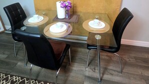 A dining area with a glass table, black chairs, and a yellow curtain.