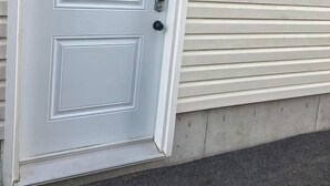 A white door with a rectangular panel design, a keyhole, and a doorbell.