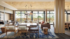 A spacious living area with a large wooden ceiling, a dining table, sofas, and chairs.
