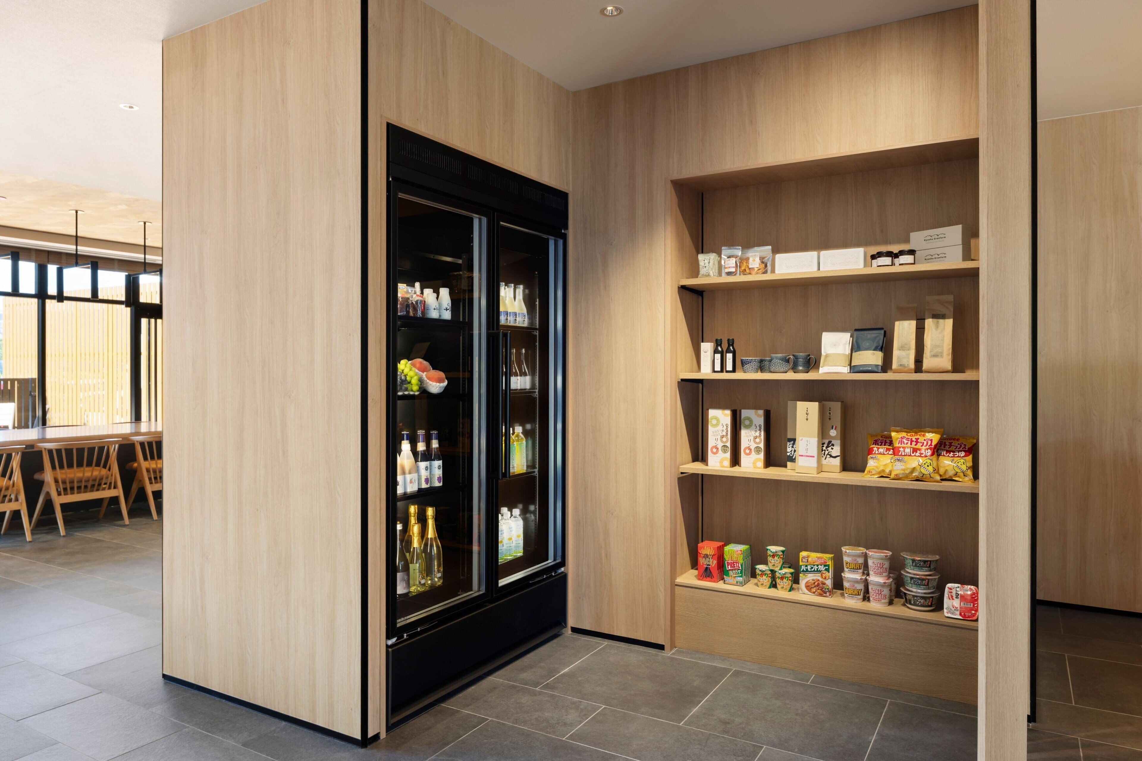 Un interior moderno con un panel de madera, un expositor refrigerado y estantes llenos de diversos alimentos.