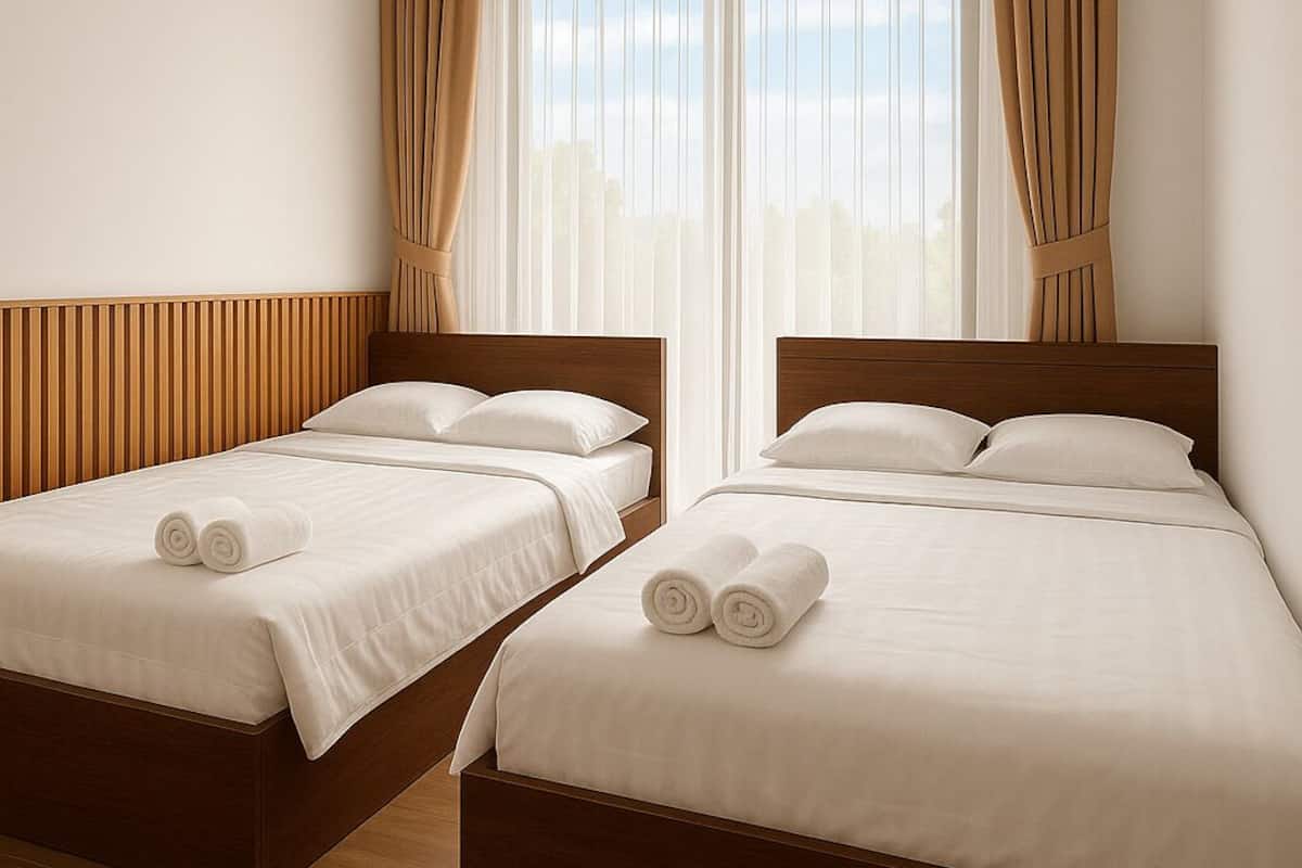 Une chambre d’hôtel avec deux lits, des têtes de lit en bois, du linge de lit blanc et un ventilateur de plafond.