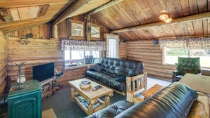 En stuga med träpanel på insidan, en soffa klädd i läder, ett soffbord i trä och en tv som står på ett träställ.