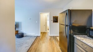 A kitchen with a black refrigerator, wooden flooring, and a white door leading to another room. - Pet-Friendly Wyandotte Apt Near Bishop Park! (Wyandotte)