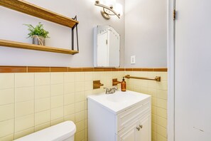 A bathroom with a white sink, a mirror, a towel rack, and a shelf with a plant. - Pet-Friendly Wyandotte Apt Near Bishop Park! (Wyandotte)