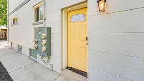 A building with a yellow door, a green electrical box, and a wall-mounted light fixture. - Pet-Friendly Wyandotte Apt Near Bishop Park! (Wyandotte)