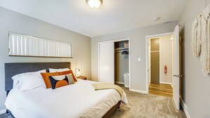 A neatly arranged bedroom with a large bed, bedside tables, a closet, and a visible door leading to another room. - Pet-Friendly Wyandotte Apt Near Bishop Park! (Wyandotte)