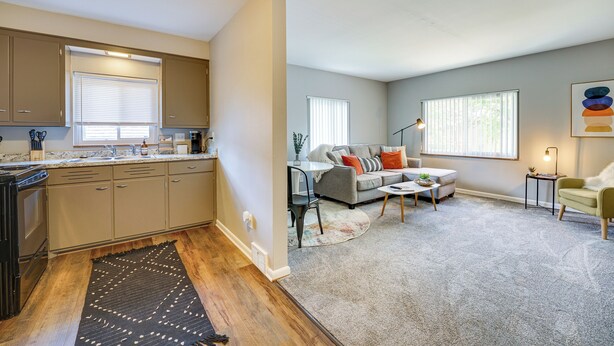 A modern kitchen with built-in appliances, a dining area with a gray sofa and a coffee table, and a living room with a large window and a floor lamp. - Pet-Friendly Wyandotte Apt Near Bishop Park! (Wyandotte)