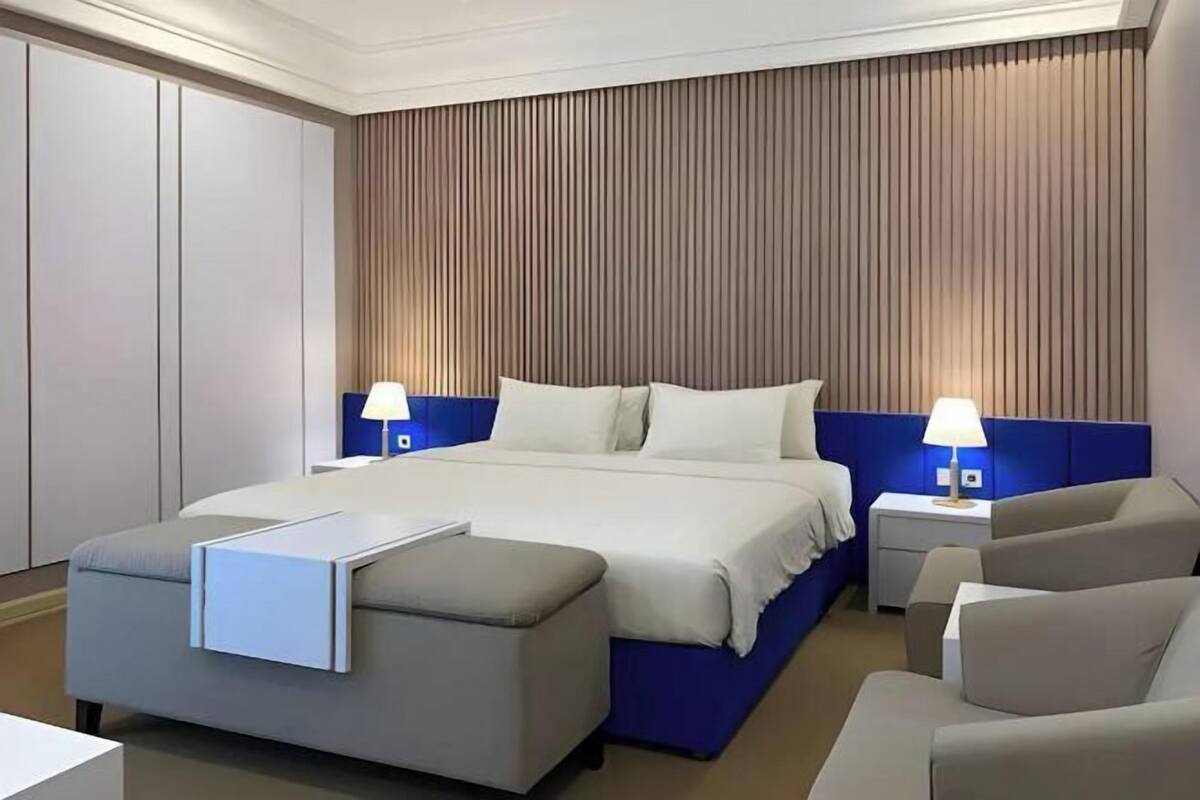 Een hotelkamer met een bed, twee nachtkastjes met lampen, een bank en een bureau met een stoel.