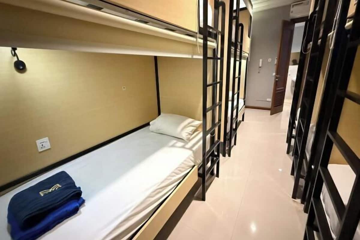 Een slaapkamer met een stapelbed, een opgevouwen handdoek en een deur naar een andere kamer.