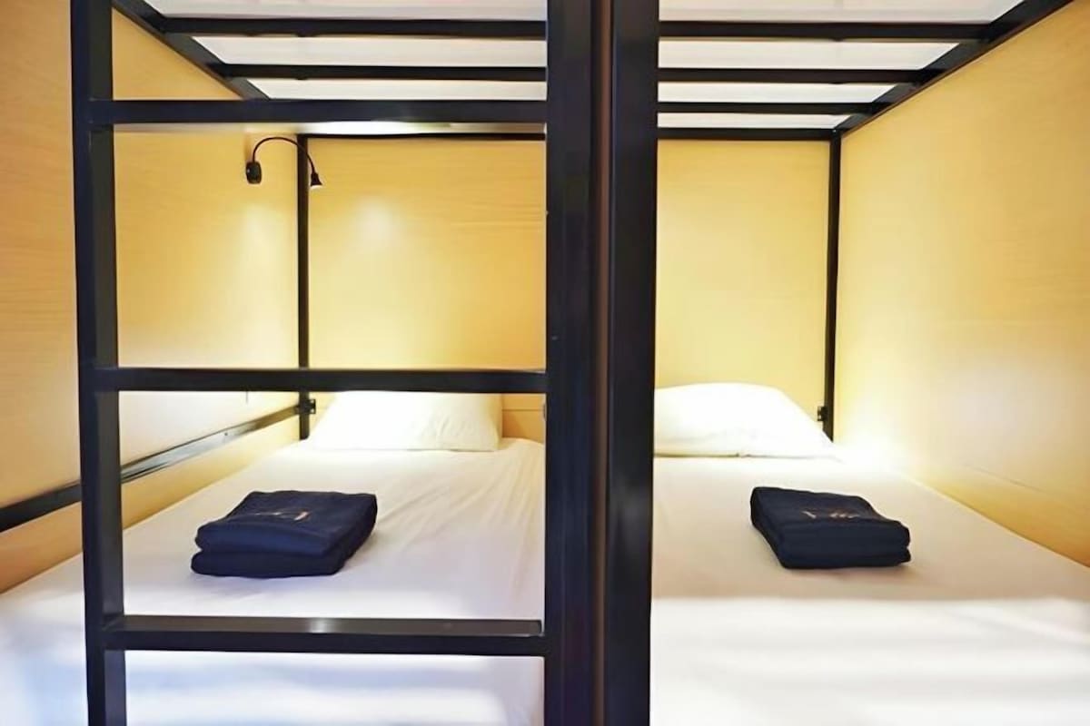 Habitación con literas de madera, dos camas y una lámpara.