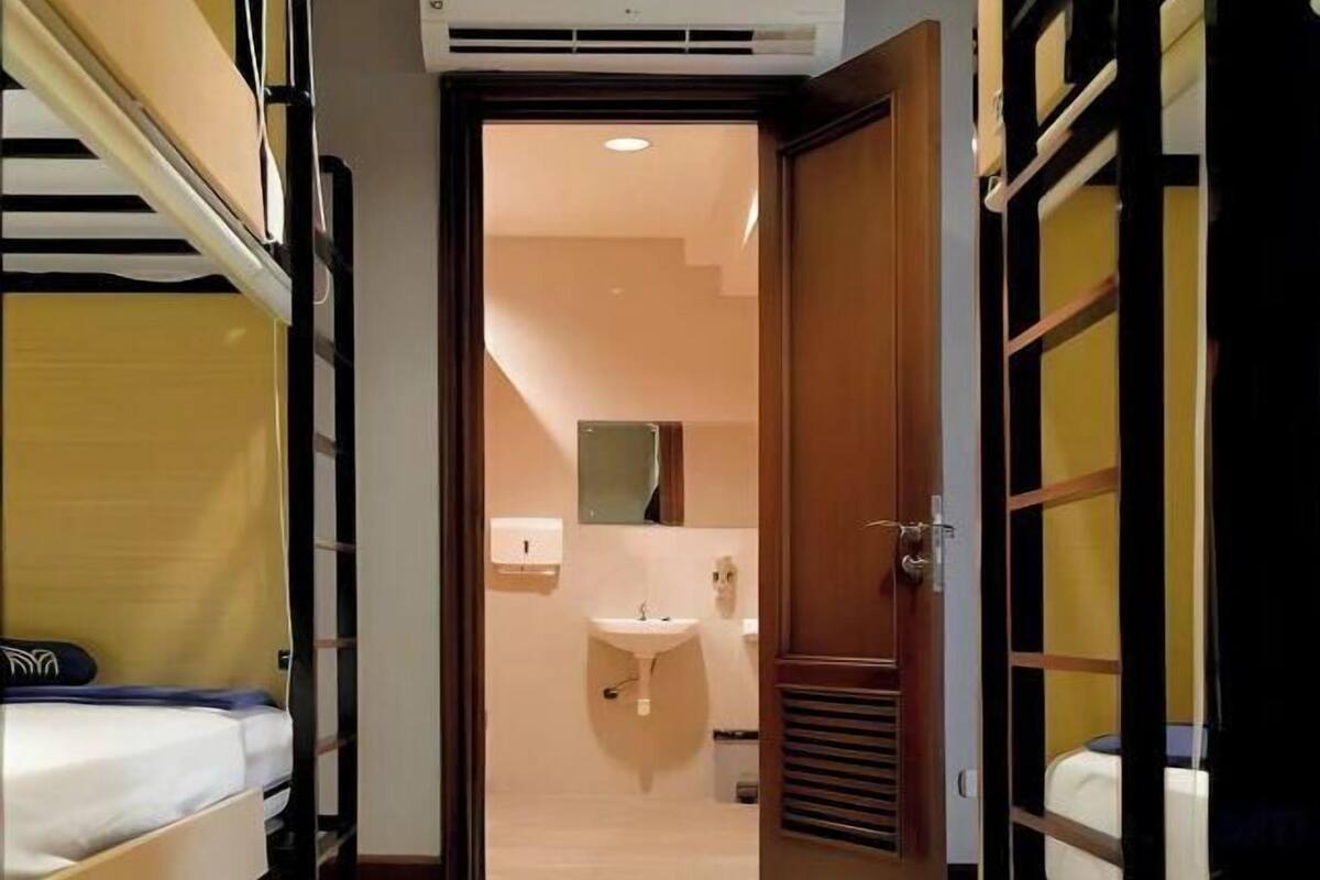 Een hotelkamer met een stapelbed, een wastafel en een houten deur.