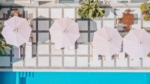 Un espace piscine aménagé sur le toit, avec de nombreux parasols roses, des chaises longues et un sol carrelé.