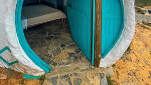 A spherical structure with a bed inside, a door, and a stone floor. - La Juanita Hostel Mesa de los Santos  (Los Santos)