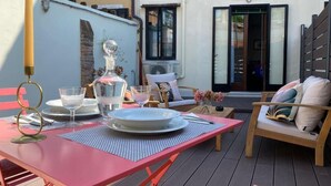 A red table set with plates, glasses, and a bottle, surrounded by wooden chairs and a bench with cushions. - Ca dei Ferro - MURANO Island, beautiful Venetian apartment with private terrace  (Venezia)