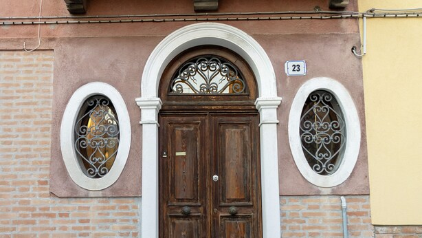 A traditional wooden door with a white pediment and two ornate windows with metal grilles. - Ca dei Ferro - MURANO Island, beautiful Venetian apartment with private terrace  (Venezia)