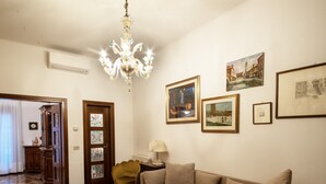 A living room with a chandelier, a sofa, a chair, and several framed pictures on the wall. - Ca dei Ferro - MURANO Island, beautiful Venetian apartment with private terrace  (Venezia)