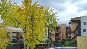 A swimming pool with tiled edges, surrounded by greenery and modern buildings in the background. - Modern apartment located in a resort style condo, pools, jacuzzi, soccer field,. (La Tebaida)