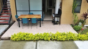 A patio area with a wooden table and chairs, a laptop on a stand, and a staircase to the left. - Modern apartment located in a resort style condo, pools, jacuzzi, soccer field,. (La Tebaida)