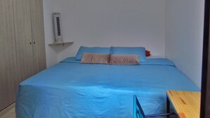 A small, single-bed room with a blue bedspread, a wooden wardrobe, and a white air conditioning unit on the wall. - Modern apartment located in a resort style condo, pools, jacuzzi, soccer field,. (La Tebaida)